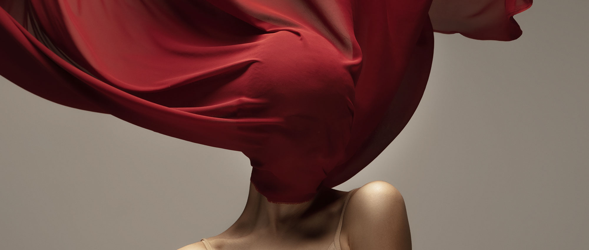 suicide loss represented by a girl with her face draped in red fabric